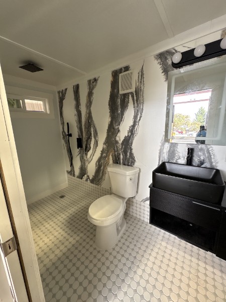 Custom bathroom with a curbless walk-in shower, statement wall, and black vessel-sink vanity