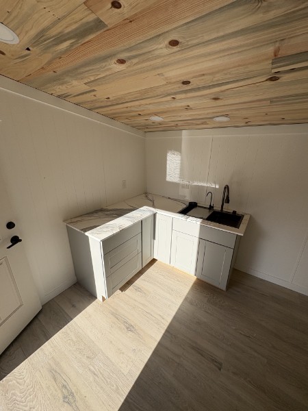 Finished ADU kitchenette remodel by K&K ProBuild with shaker cabinets, stone counters, and a natural wood plank ceiling
