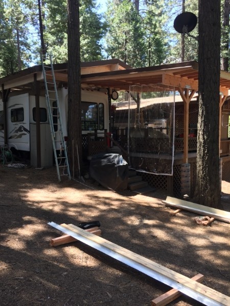Custom covered patio with brown metal roofing, built by K&K ProBuild in a wooded Southern Oregon setting