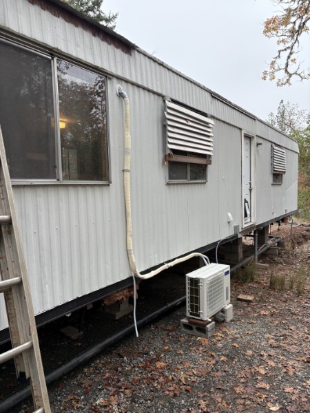 Ductless mini-split outdoor unit installed on a single-wide manufactured home