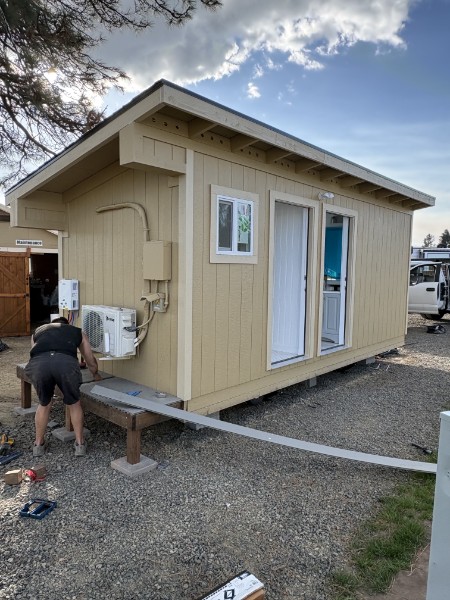 K&K ProBuild technician installing a ductless mini-split heat pump on the exterior of a finished ADU in Southern Oregon