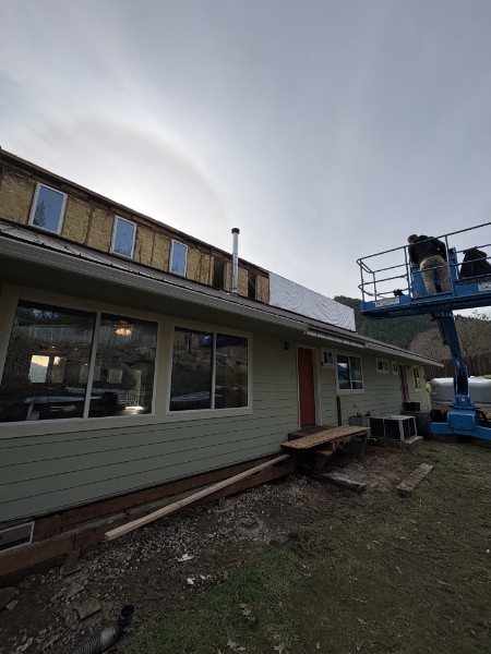 Siding replacement in progress on a single-story Southern Oregon home, worked from a lift